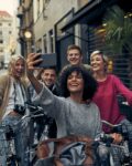 Friends Riding Bicycles In A City. Cycling in pedestrian zone and making selfie.